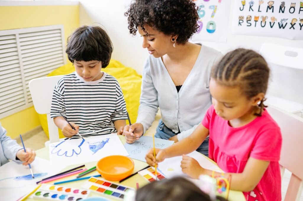 Children painting with a teacher